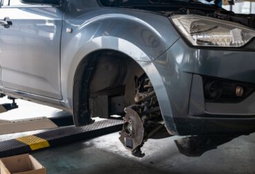 Repair and change parts a pickup truck with damaged axle and wheel lifted by scissor lift in garage Repair and change parts a pickup truck with damaged axle and wheel lifted by scissor lift in garage workshop